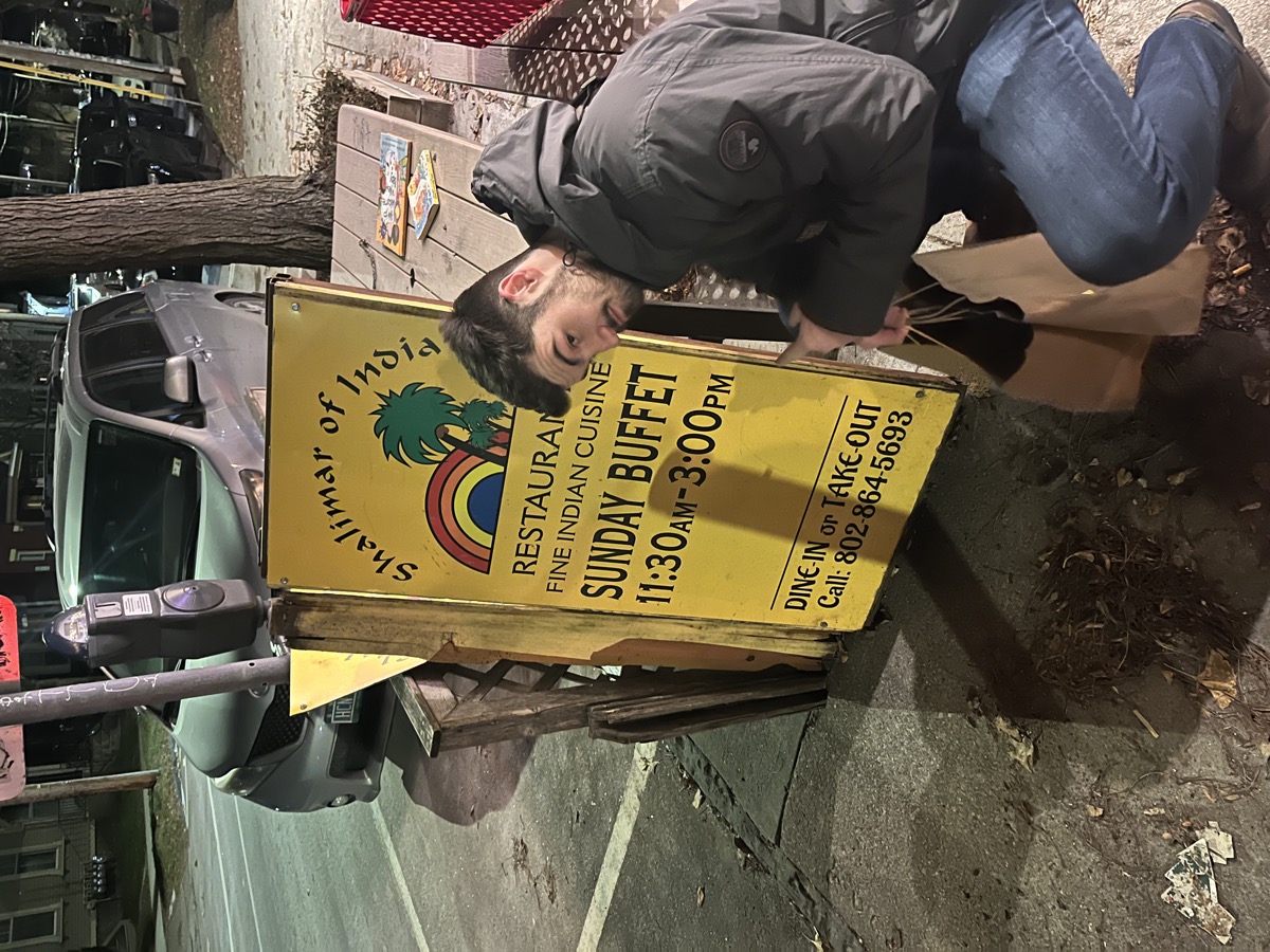 Matt Kahler crouching next to a Sunday buffet restaurant sign