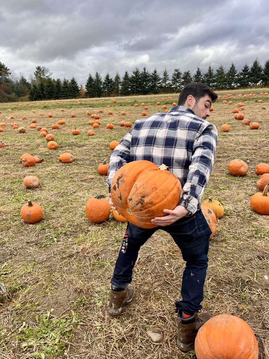 Matt Kahler hoisting an enormous pumpkin in a pumpkin patch