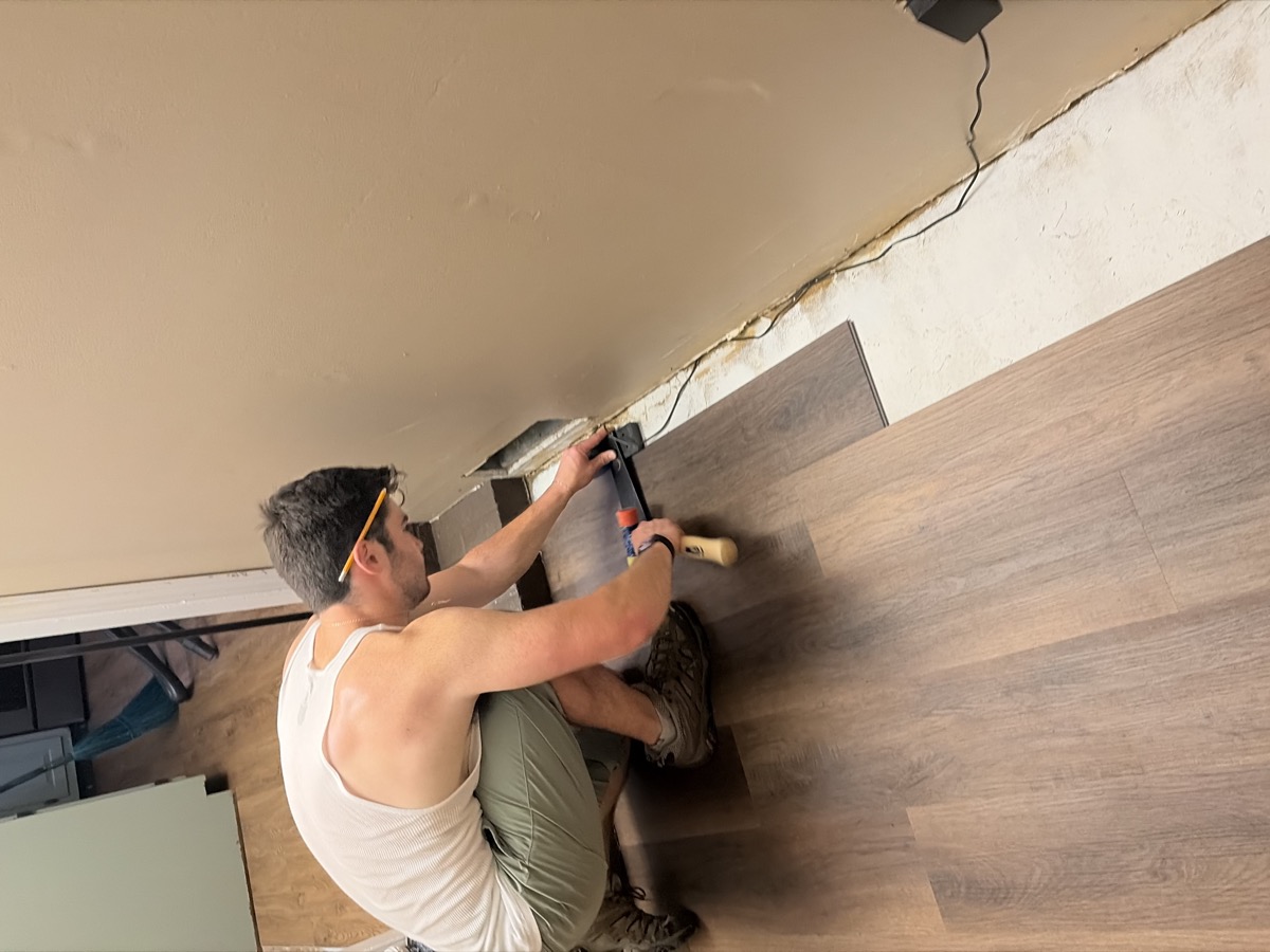 Matt Kahler installing new flooring with a mallet